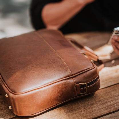 Close up view of leather laptop bag, showcasing front sleeve pocket.