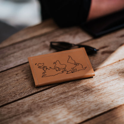 Front view (with engraved world map) of leather passport holder and travel wallet.