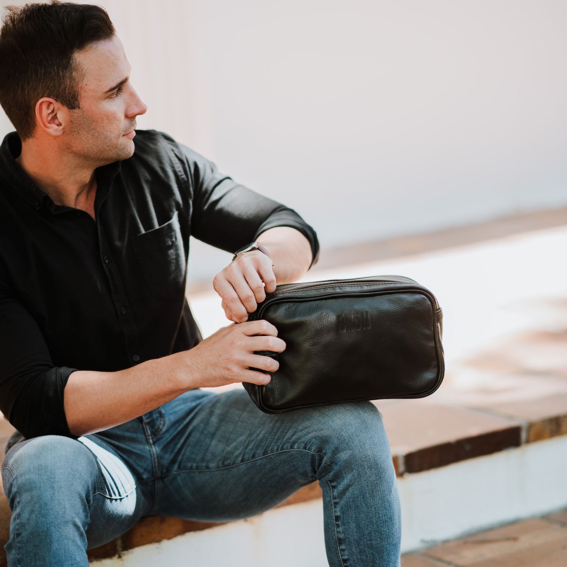 Front view of the leather toiletry bag, showcasing the handle and top zipper.