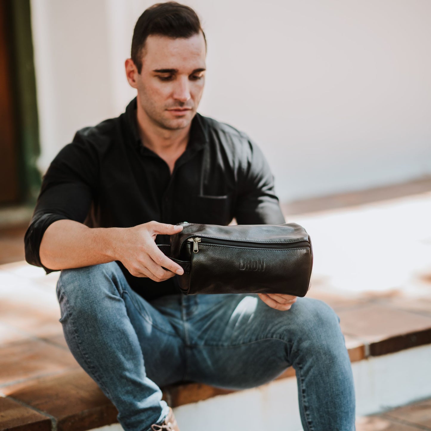 Front view of the leather toiletry bag, showcasing the handle and top zipper.