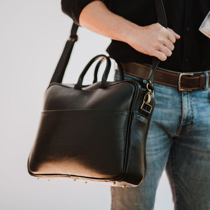 Front and side view of leather laptop bag, showcasing front sleeve pocket, shoulder straps and handles.