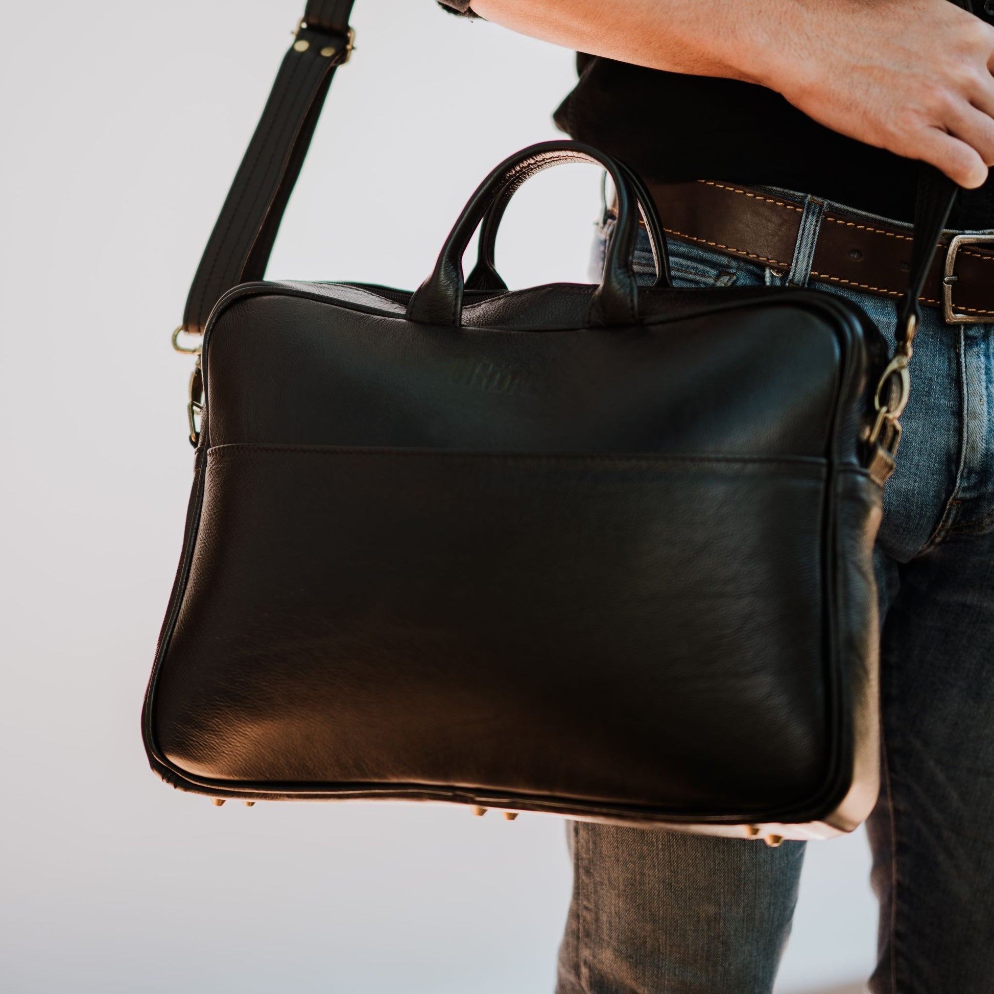 Front view of leather laptop bag, showcasing front sleeve pocket and handles.