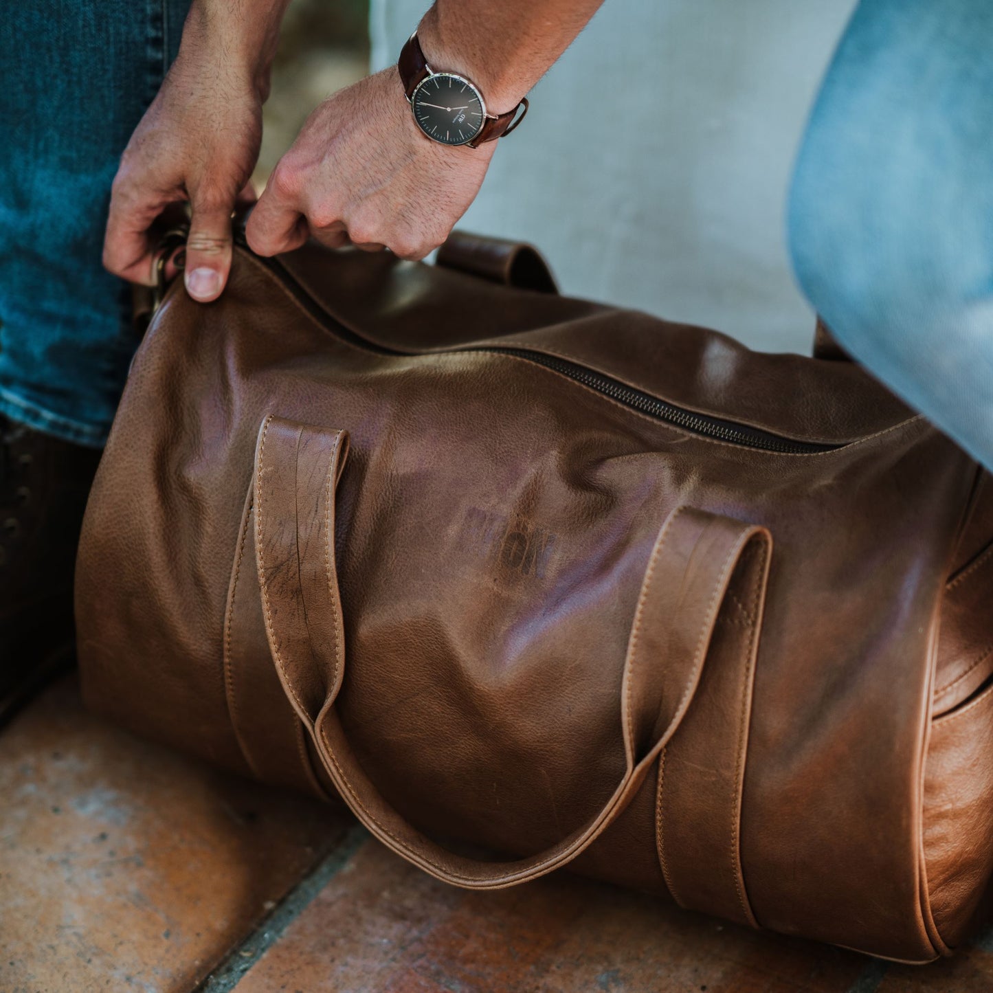 Front and top view of leather duffel bag, showcasing the handles and zipper.