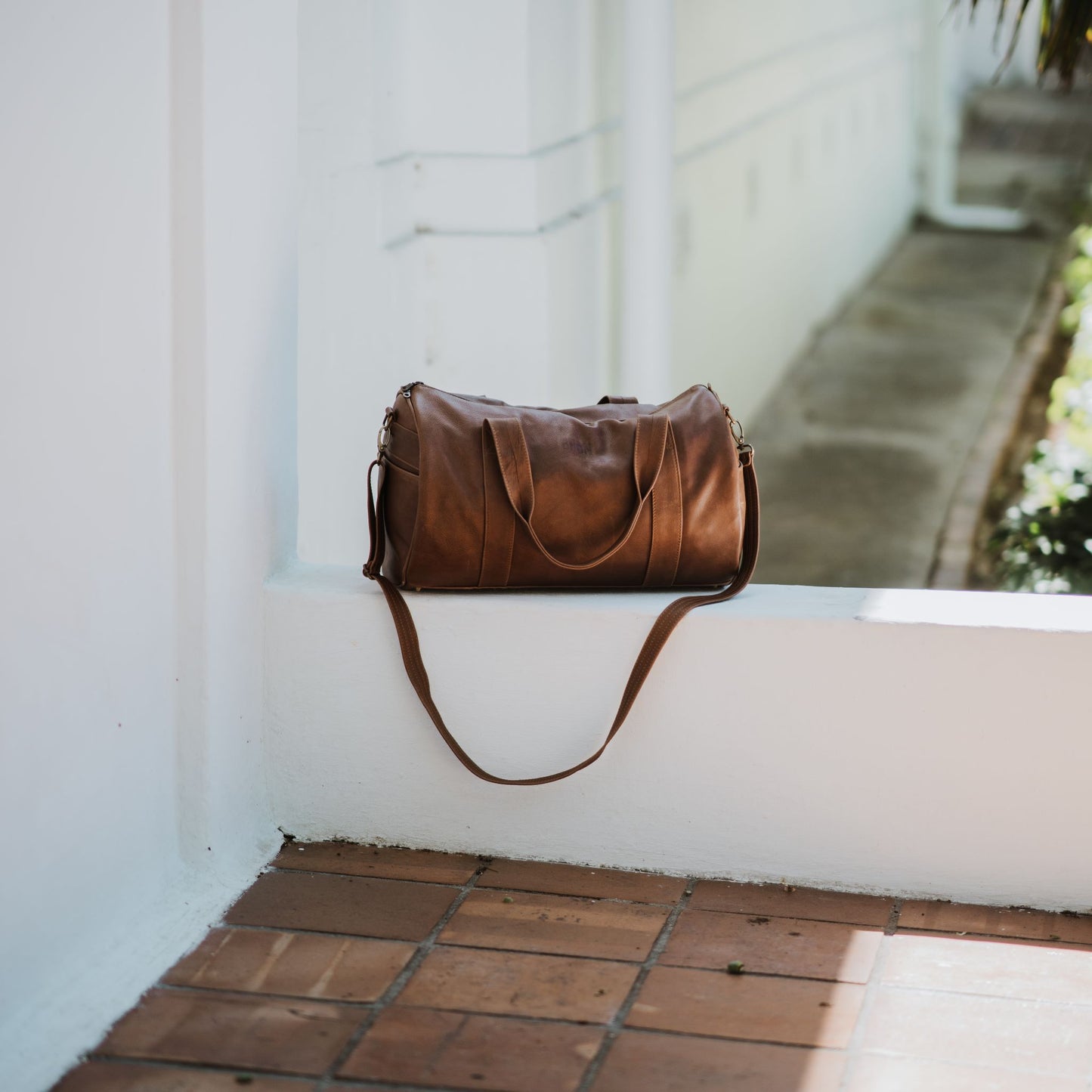 Front view of leather duffel bag, showcasing the handles and shoulder strap.