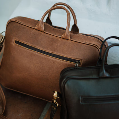 Back view of leather laptop bag, showcasing zip pocket and handles.