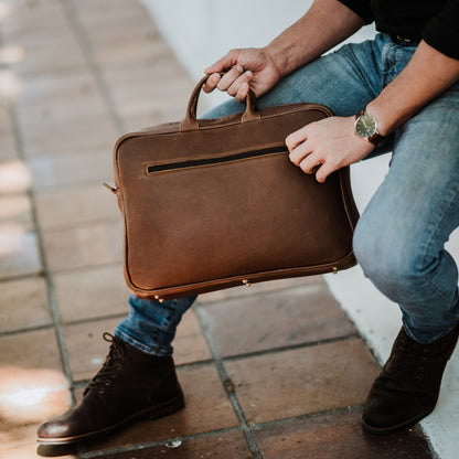 Back view of leather laptop bag, showcasing zip pocket and handles.