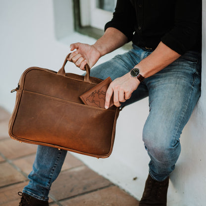 Front view of leather laptop bag, showcasing front sleeve pocket and handles.