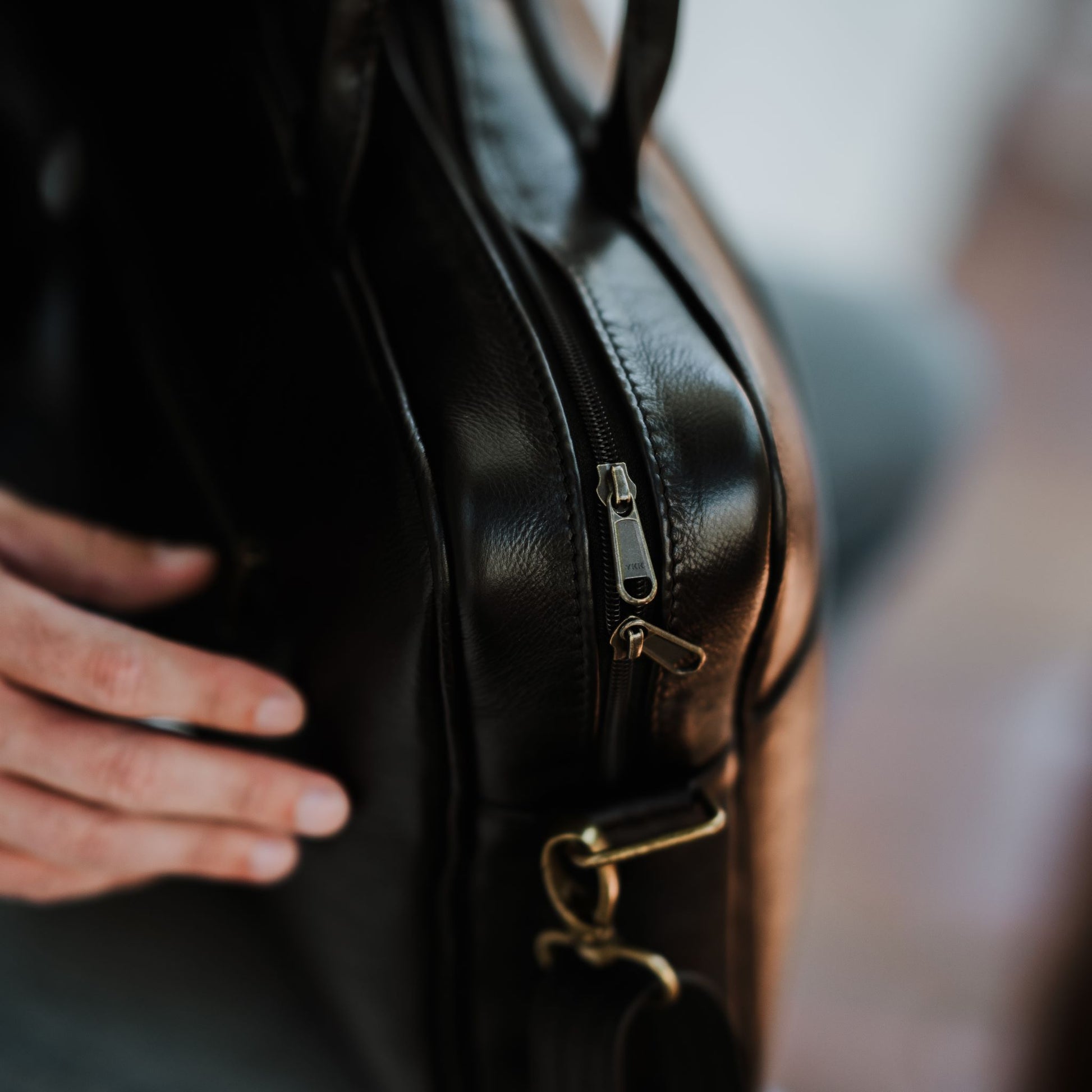 Close up side view of leather laptop bag, showcasing top zipper.