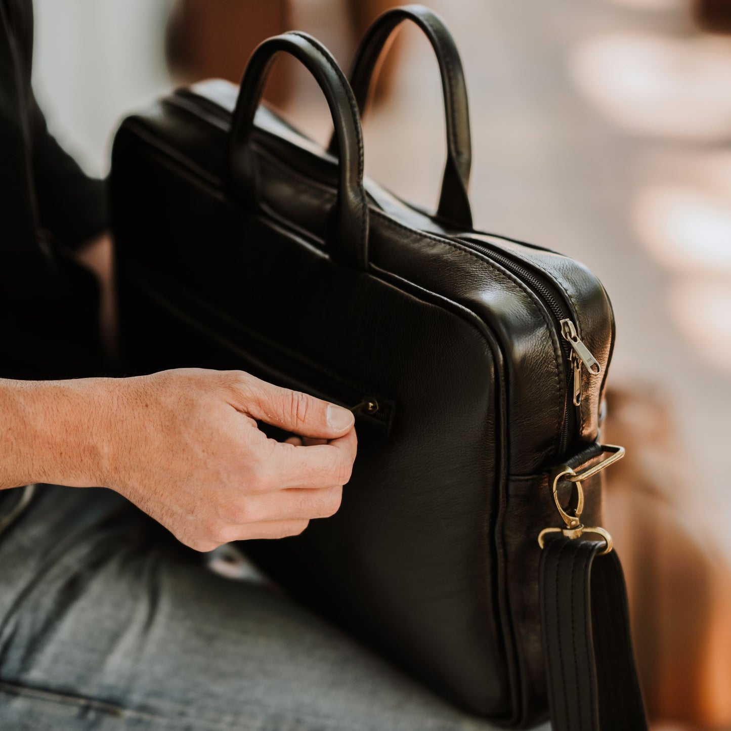 Back and side view of leather laptop bag, showcasing back zip pocket, shoulder straps and handles.