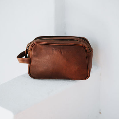 Front view of the leather toiletry bag, showcasing the handle and top zipper.