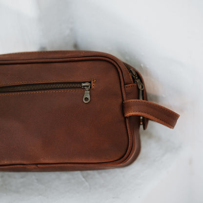 Back view of the leather toiletry bag, showcasing the handle and back zipper pocket.