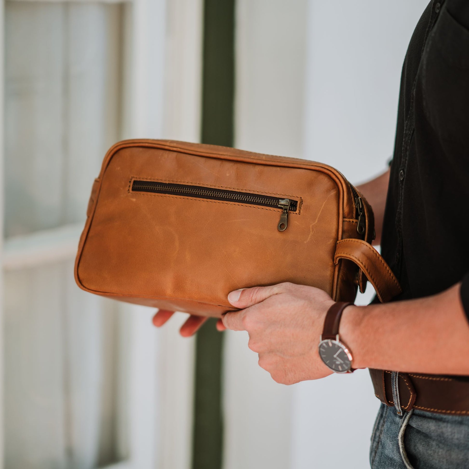 Back view of the leather toiletry bag, showcasing the handle and back zipper pocket.