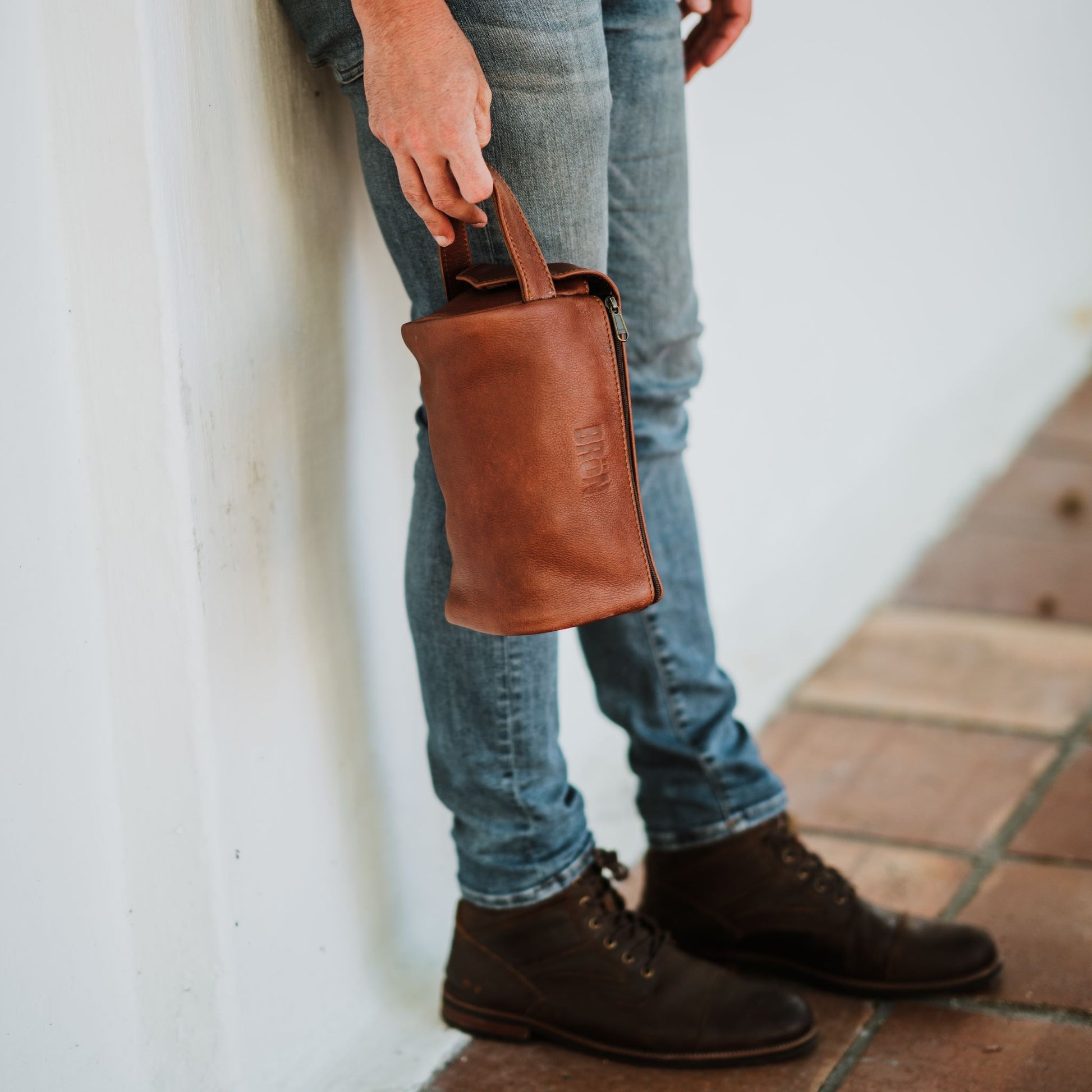 Front view of the leather toiletry bag, showcasing the handle and top zipper.