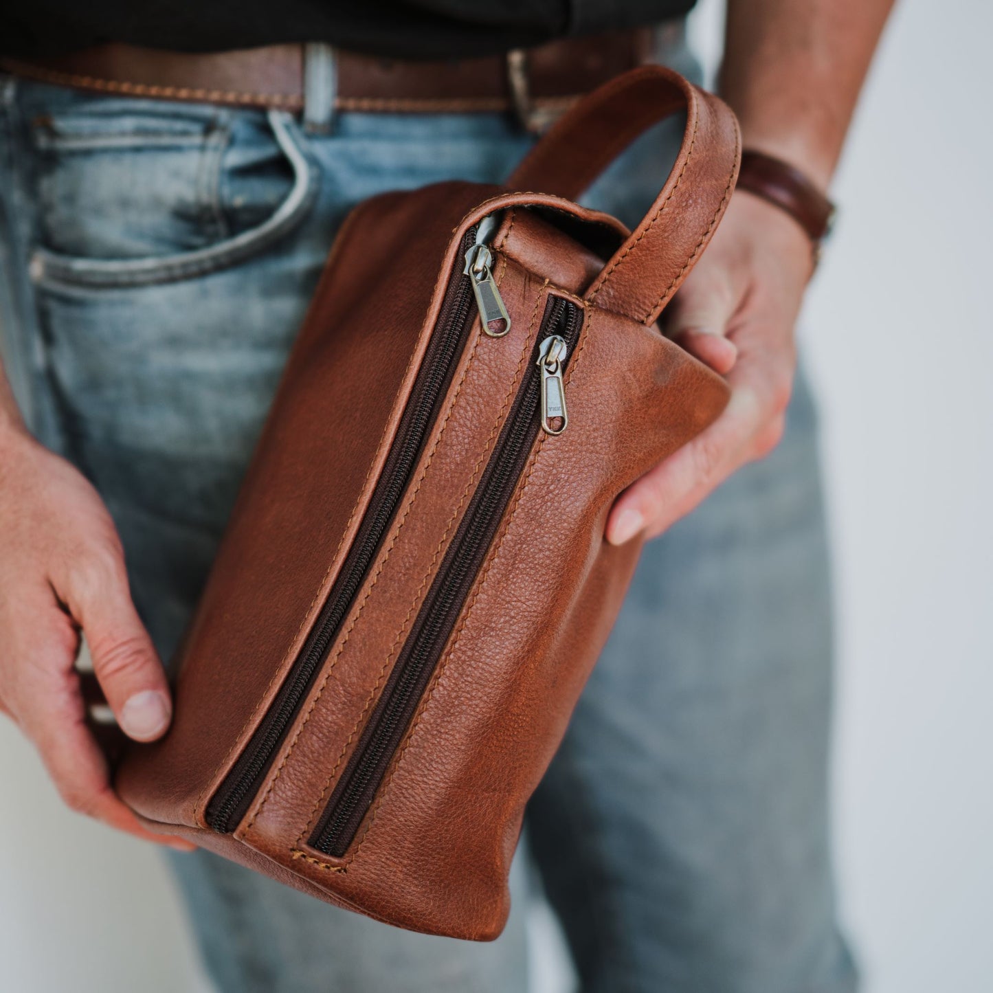 Back view of the leather toiletry bag, showcasing the handle and back zip pocket.