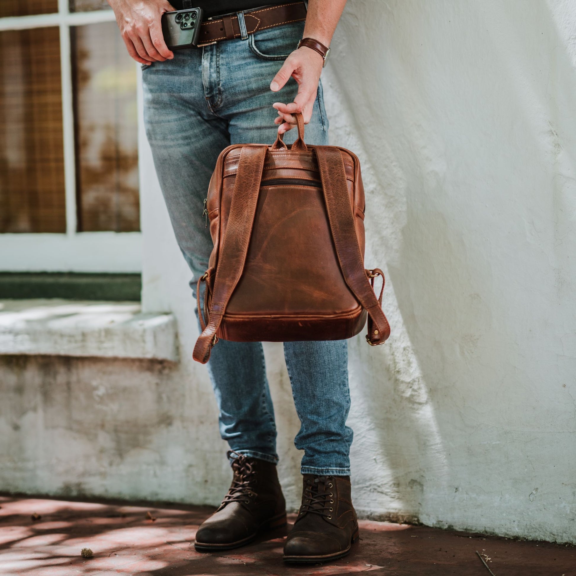 Back view of the leather laptop backpack, showcasing the back zip pocket, shoulder straps and handle.