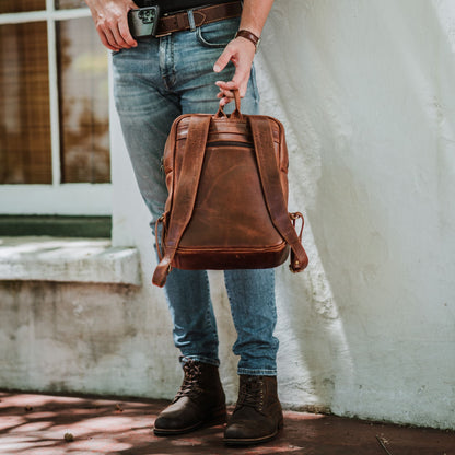 Back view of the leather laptop backpack, showcasing the back zip pocket, shoulder straps and handle.