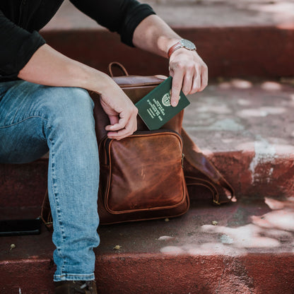 Front view of the leather laptop backpack, showcasing the front zip pocket, shoulder straps and handle.