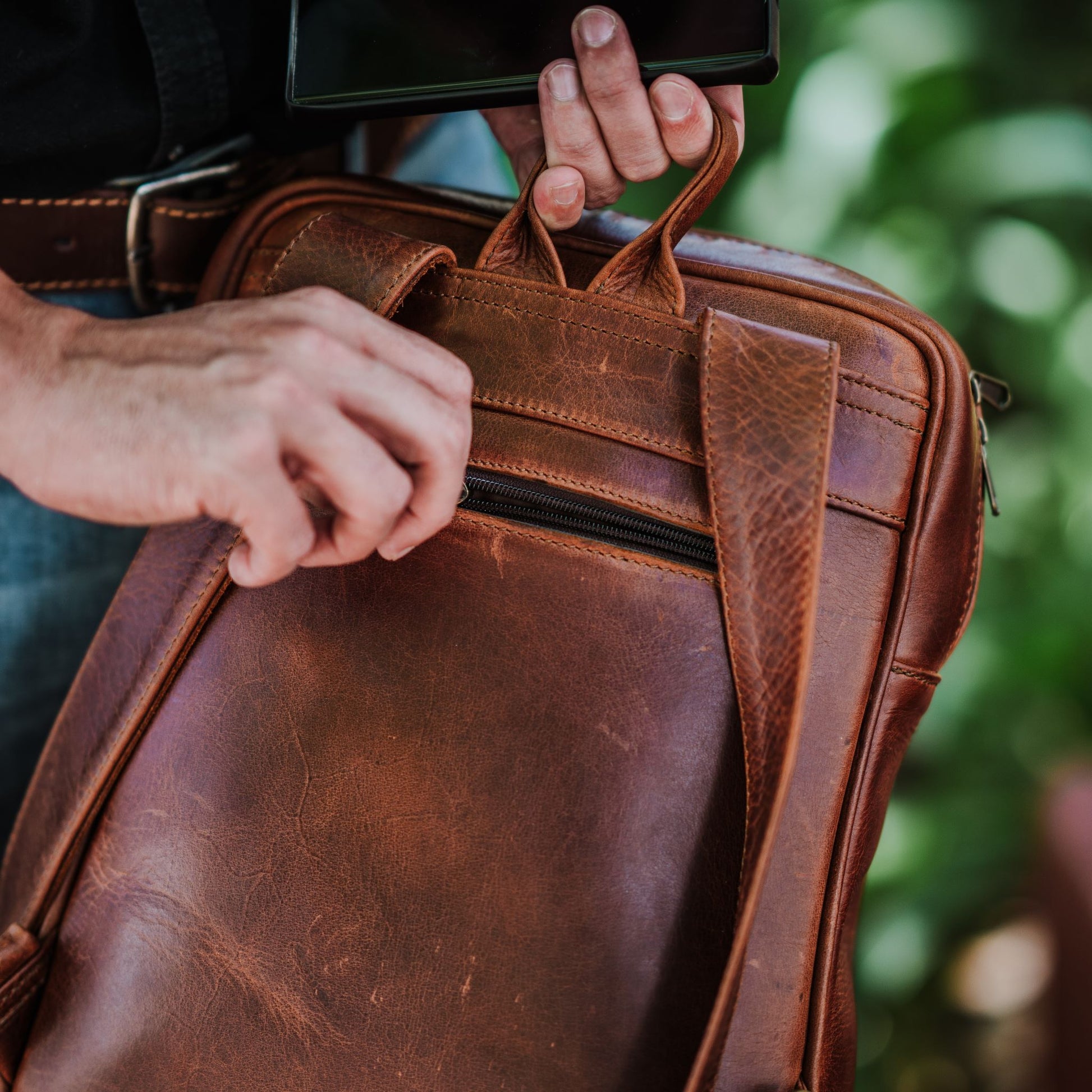 Back view of the leather laptop backpack, showcasing the back zip pocket, shoulder straps and handle.