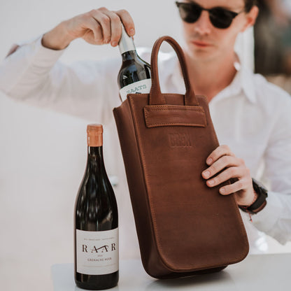 Front view of the leather wine carrier, showcasing the handles and two bottles of wine.