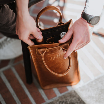 Top view of the leather wine carrier, showcasing the handles and two bottles of wine inside.