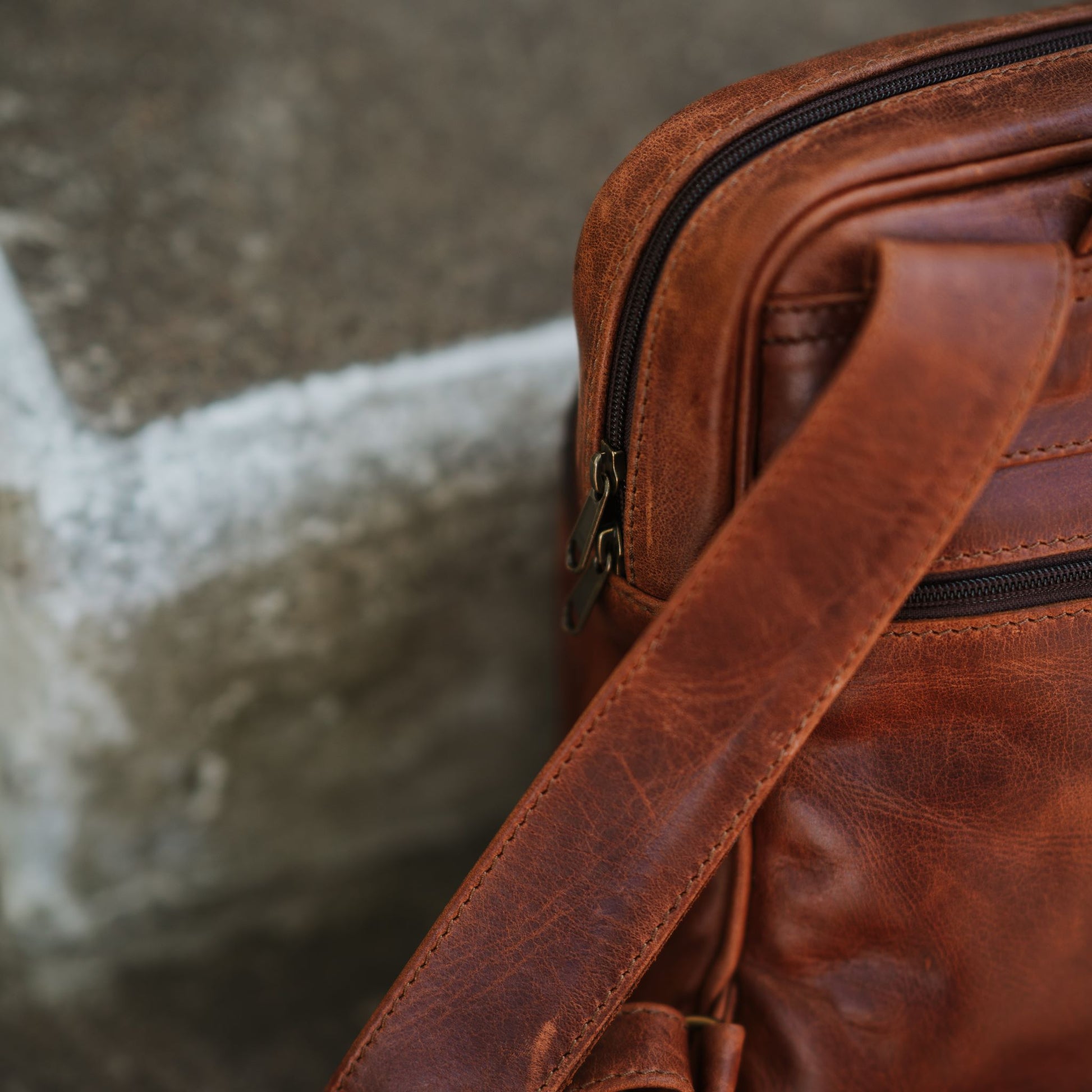 Close up view of the small leather backpack, showcasing the back zip pocket and shoulder straps.