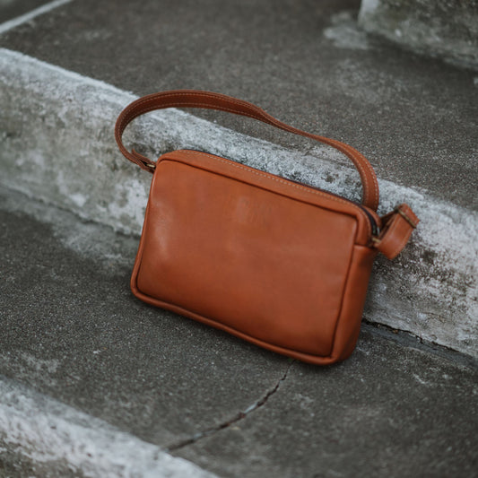 Front view of the leather sling bag, showcasing the adjustable shoulder strap.