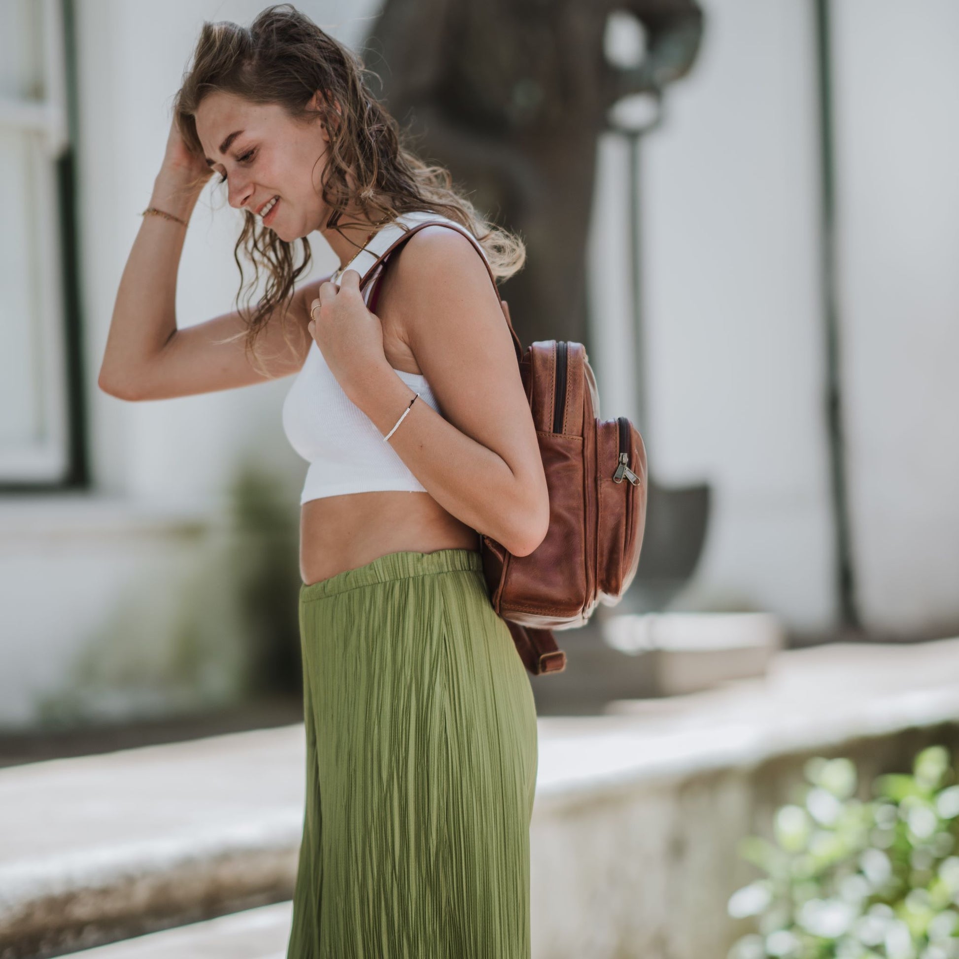 Side view of the small leather backpack, showcasing the front zip pocket and shoulder straps.