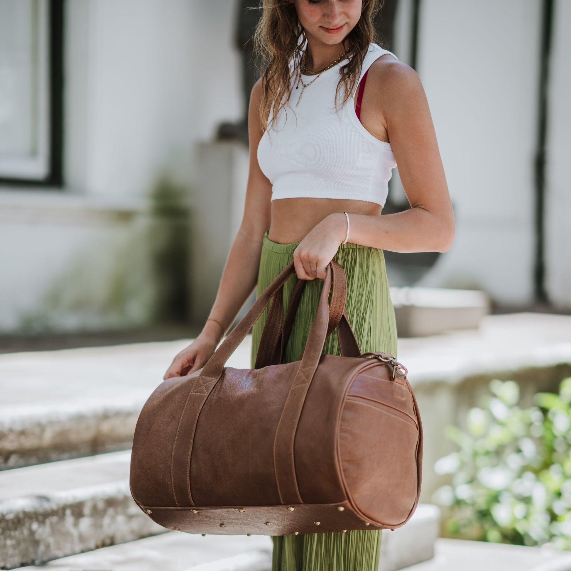 Front and side view of leather duffel bag, showcasing the handles and shoulder strap.